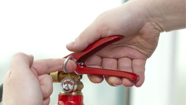 A hand pulling the pin from a fire extinguisher