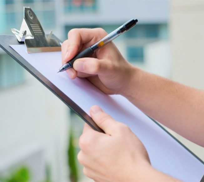 A person holding a pen to a piece of paper on a clipboard
